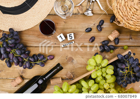 Grapes, bottle of wine, glass with wine, hat on a wooden background. View from above. Winemaking Grapes, bottle of wine, glass with wine, hat on a wooden background. View from above. Winemaking 68007849
