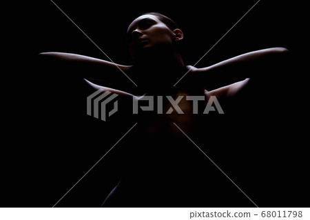 Nude Woman silhouette under light in the dark Nude Woman silhouette under light in the dark 68011798