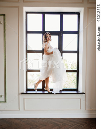 beautiful bride stands on sill of window. 68012858