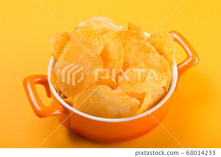 large yellow potato chips in an orange pan, on a large yellow potato chips in an orange pan, on a 68014233