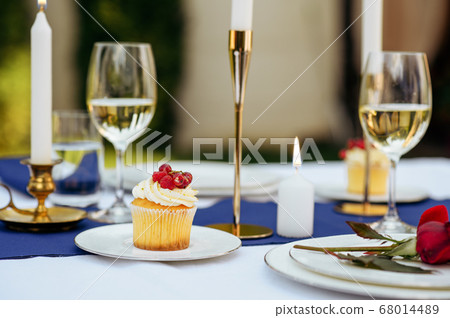 Table setting, glasses, candles, flower and sweets 68014489