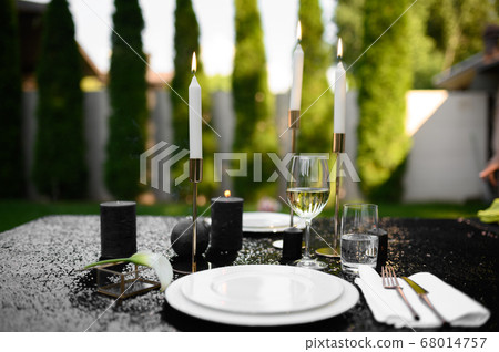Table setting, glasses, candles and plate on black 68014757