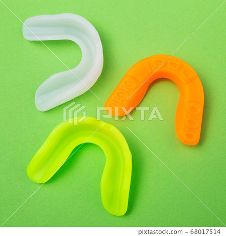 three colored boxing mouth guards lie on a green 68017514