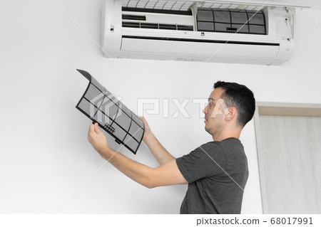 The guy cleans the filter of the home air The guy cleans the filter of the home air 68017991