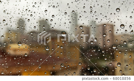 Raindrops on office window with blur grey sky background. Office window covered with closeup rain water. 68018856