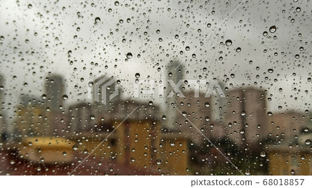 Raindrops on office window with blur grey sky background. Office window covered with closeup rain water. Raindrops on office window with blur grey sky background. Office window covered with closeup rain water. 68018857
