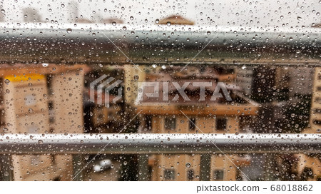 Raindrops on office window with blur grey sky background. Office window covered with closeup rain water. Raindrops on office window with blur grey sky background. Office window covered with closeup rain water. 68018862