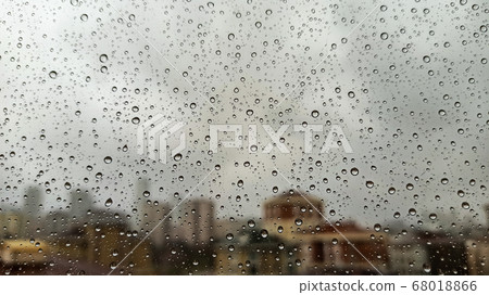 Raindrops on office window with blur grey sky background. Office window covered with closeup rain water. Raindrops on office window with blur grey sky background. Office window covered with closeup rain water. 68018866