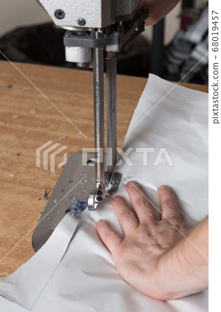 cloth cutting with an electric knife, a man's hand cloth cutting with an electric knife, a man's hand 68019457