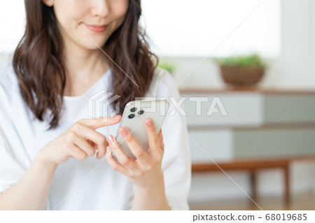 A young woman who operates a smartphone in the living room Focuses on the smartphone 68019685