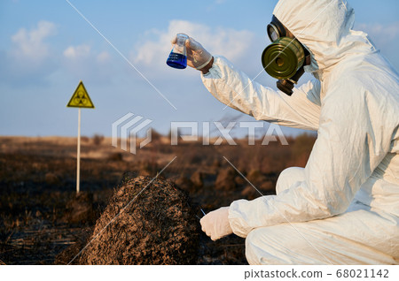 Male scientist doing research work in burnt field. 68021142
