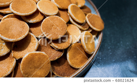 A plate of Dutch Mini Pancakes, poffertjes with peanut butter on the wooden background A plate of Dutch Mini Pancakes, poffertjes with peanut butter on the wooden background 68021624