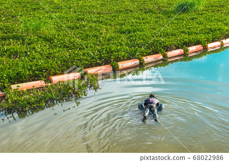Hunter fisherman with a speargun on a life ring looks under the water in search of fish in the evening. Hunter fisherman with a speargun on a life ring looks under the water in search of fish in the evening. 68022986