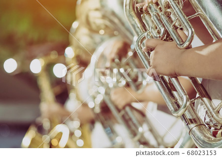 Male student with friends blow the euphonium with the band for performance on stage at night. Male student with friends blow the euphonium with the band for performance on stage at night. 68023153