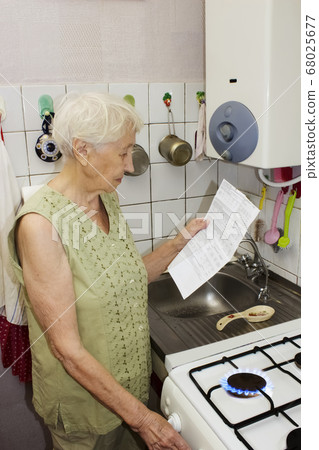 The senior woman at home and examines gas bill 68025677