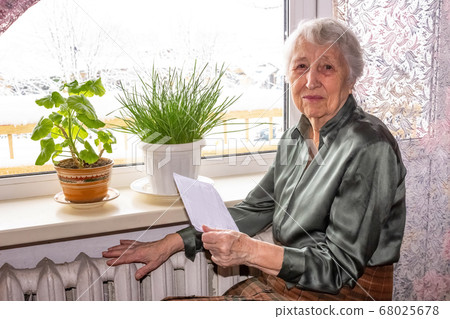 Woman holding cash in front of heating radiator. 68025678