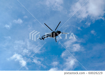 helicopter in the blue cloudy sky from beneath 68026229