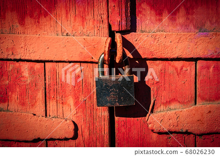 Closed lock on gates made of wooden planks and painted in red, retro 68026230