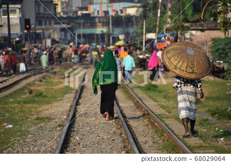People walking along the Dhaka Railway in the capital of Bangladesh Muslim women in hijabs and men carrying bamboo baskets 68029064