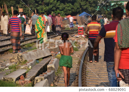Dhaka, the capital of Bangladesh, a girl walking along the tracks mixed with an adult carrying trash collected 68029091