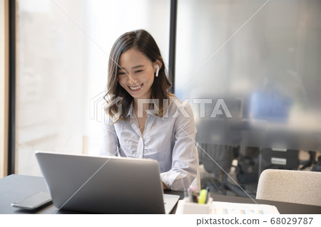 A woman in her 30s who telework with a computer with full wireless earphones 68029787