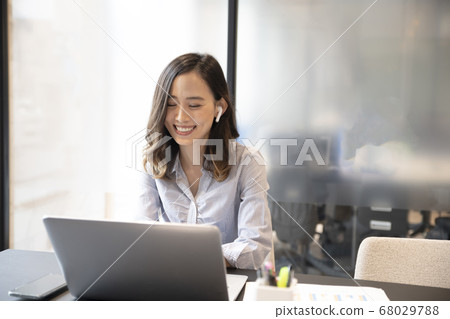 A woman in her 30s who telework with a computer with full wireless earphones A woman in her 30s who telework with a computer with full wireless earphones 68029788