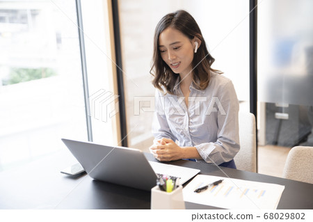 A woman in her 30s who telework with a computer with full wireless earphones 68029802
