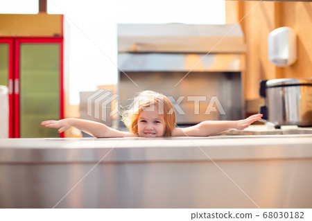 little girl behind an empty counter, serving table 68030182
