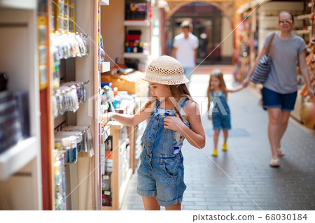 little girl chooses Souvenirs in street shop hotel 68030184