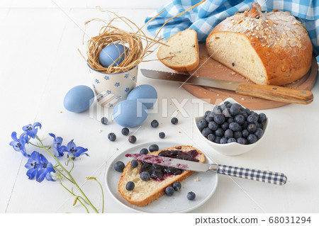Breakfast with Easter symbols, traditional Czech pastry Mazanec, Pomlazka and eggs in blue style. Breakfast with Easter symbols, traditional Czech pastry Mazanec, Pomlazka and eggs in blue style. 68031294