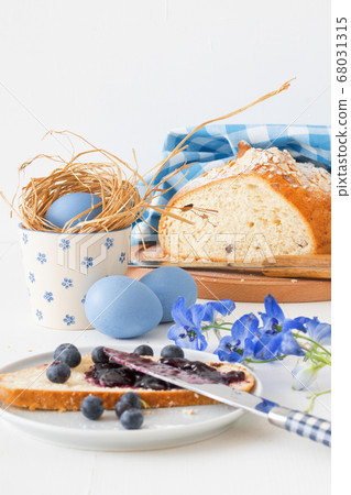 Breakfast with Easter symbols, traditional Czech pastry Mazanec, Pomlazka and eggs in blue style. Breakfast with Easter symbols, traditional Czech pastry Mazanec, Pomlazka and eggs in blue style. 68031315