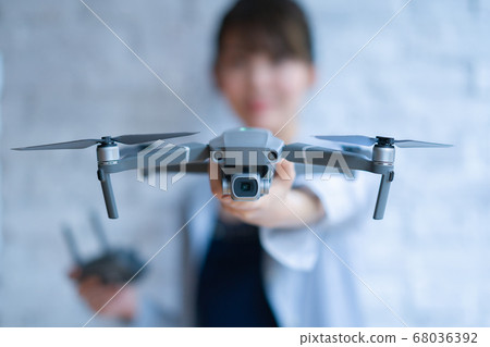 Drone business casual office woman 1 person business talk aerial view window near window operation hobby airplane 68036392