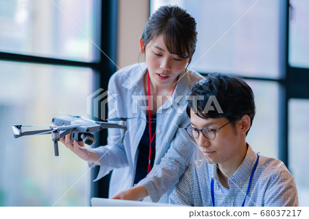 Drone business casual office two male and female business talk aerial view aerial view window hand control hobby flight 68037217