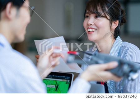 Drone business casual office two male and female business talk aerial view aerial view window hand control hobby flight 68037240