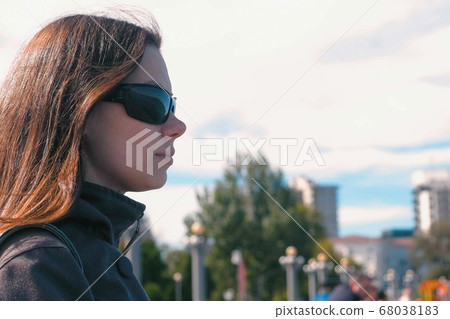 Young brunette woman in sunglasses looking at the sea in autumn. Young brunette woman in sunglasses looking at the sea in autumn. 68038183