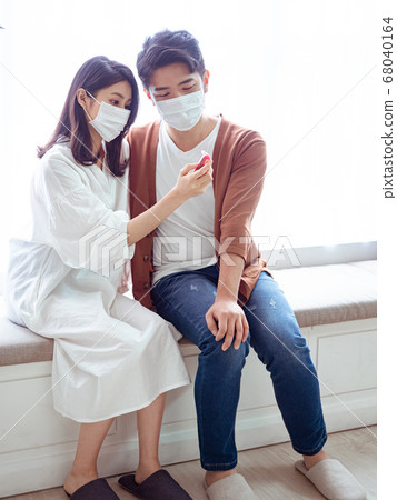 Young asian couple wearing surgical mask and using 68040164