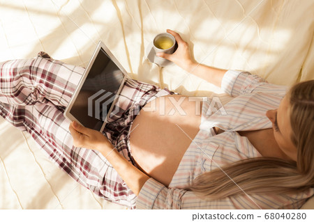 pregnant woman at home using digital tablet 68040280