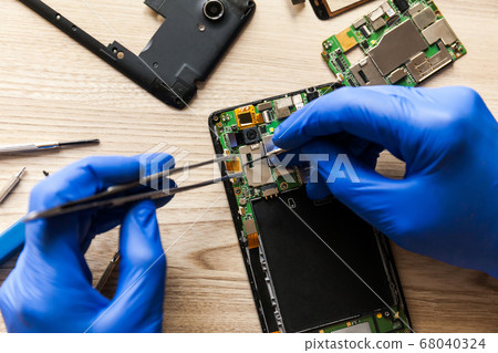 Technician repairing mobile phone at table, 68040324