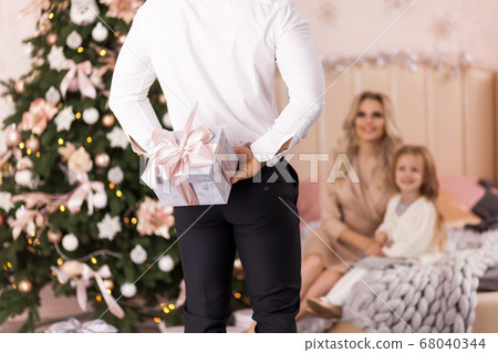 Man hiding gift for family having fun near 68040344