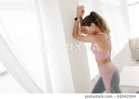 young sports girl in sportswear is doing yoga and stretching at home in a bright room. young sports girl in sportswear is doing yoga and stretching at home in a bright room. 68042004