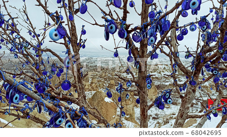 Blue Evil eye charms hang on the tree in Cappadocia, Turkey Blue Evil eye charms hang on the tree in Cappadocia, Turkey 68042695