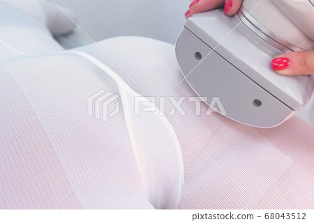 Cosmetologist makes a woman in nylon suit lpg massage booty close-up view. Cosmetologist makes a woman in nylon suit lpg massage booty close-up view. 68043512