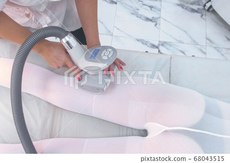 Beautician makes a woman in nylon suit lpg massage on the leg. Leg and hands close-up. 68043515