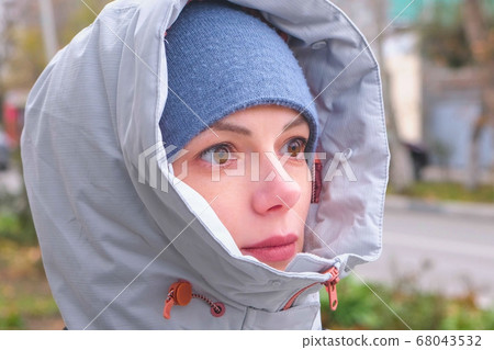 Woman in hat and hood looking into the distance and smiling. Woman in hat and hood looking into the distance and smiling. 68043532