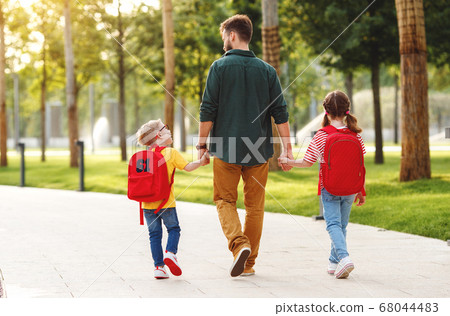 Children walking to school with father. 68044483