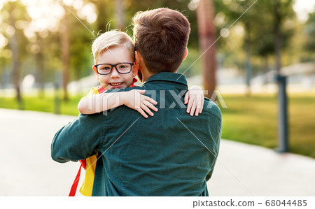 Happy son hugging father before school. Happy son hugging father before school. 68044485