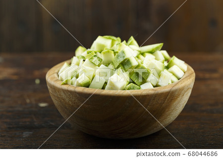 Sliced zucchini in a bowl on a wooden background. 68044686