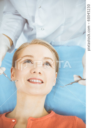 Happy smiling woman is being examined by dentist at dental clinic. Healthy teeth and medicine, stomatology concept 68045230