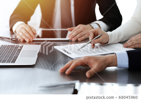 Business people discussing contract while working together in sunny modern office. Unknown businessman and woman with colleagues or lawyers at meeting Business people discussing contract while working together in sunny modern office. Unknown businessman and woman with colleagues or lawyers at meeting 68045960
