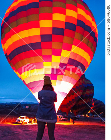 Young woman watching hot air balloons at early morning with rocky landscape in Cappadocia, Turkey 68046086